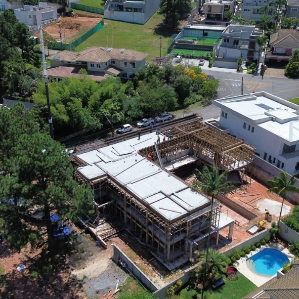 Residência em construção ao lado de casa com piscina